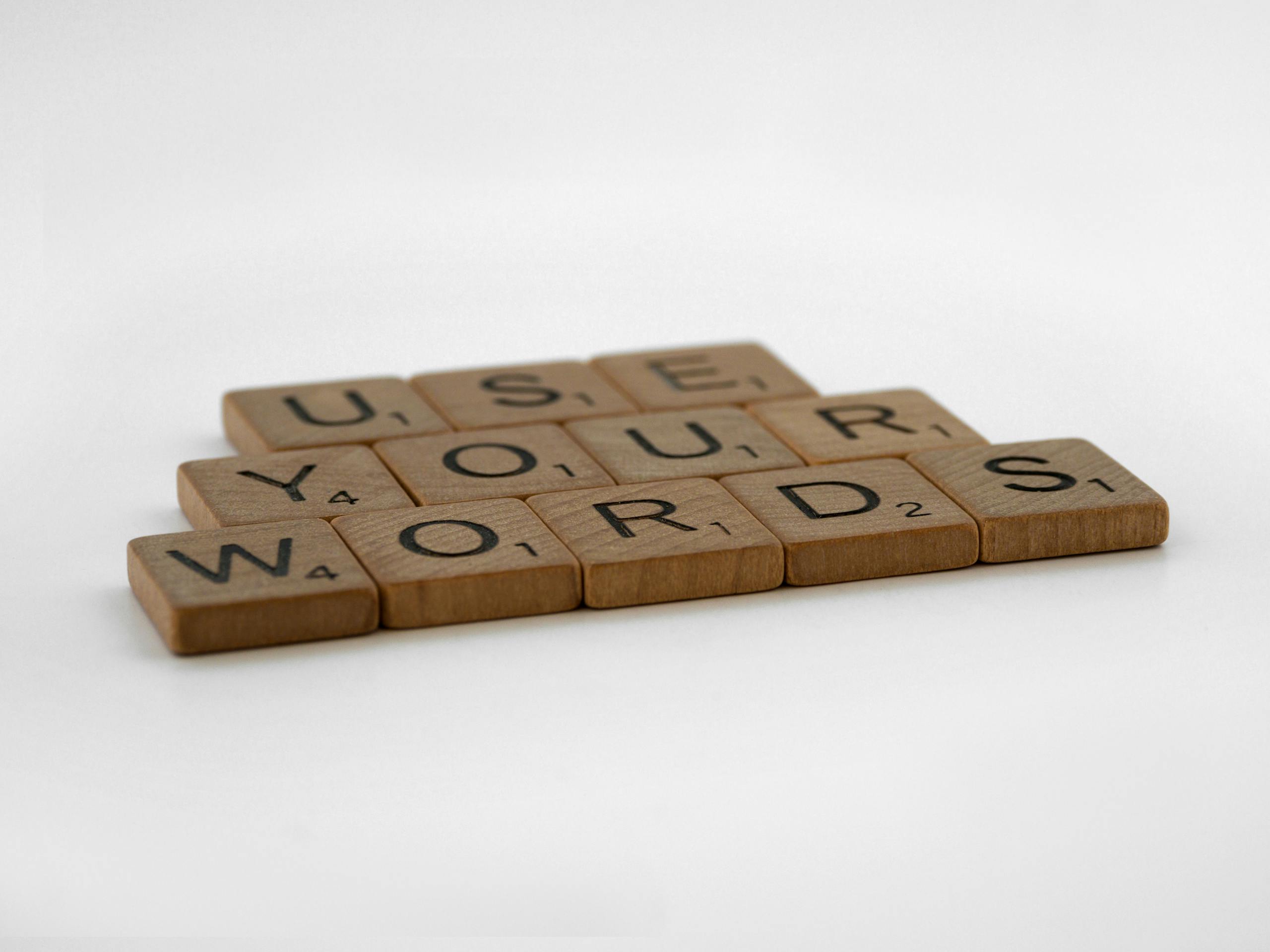 Close-up of wooden letter tiles spelling 'Use Your Words' on a white background, perfect for communication and language themes.