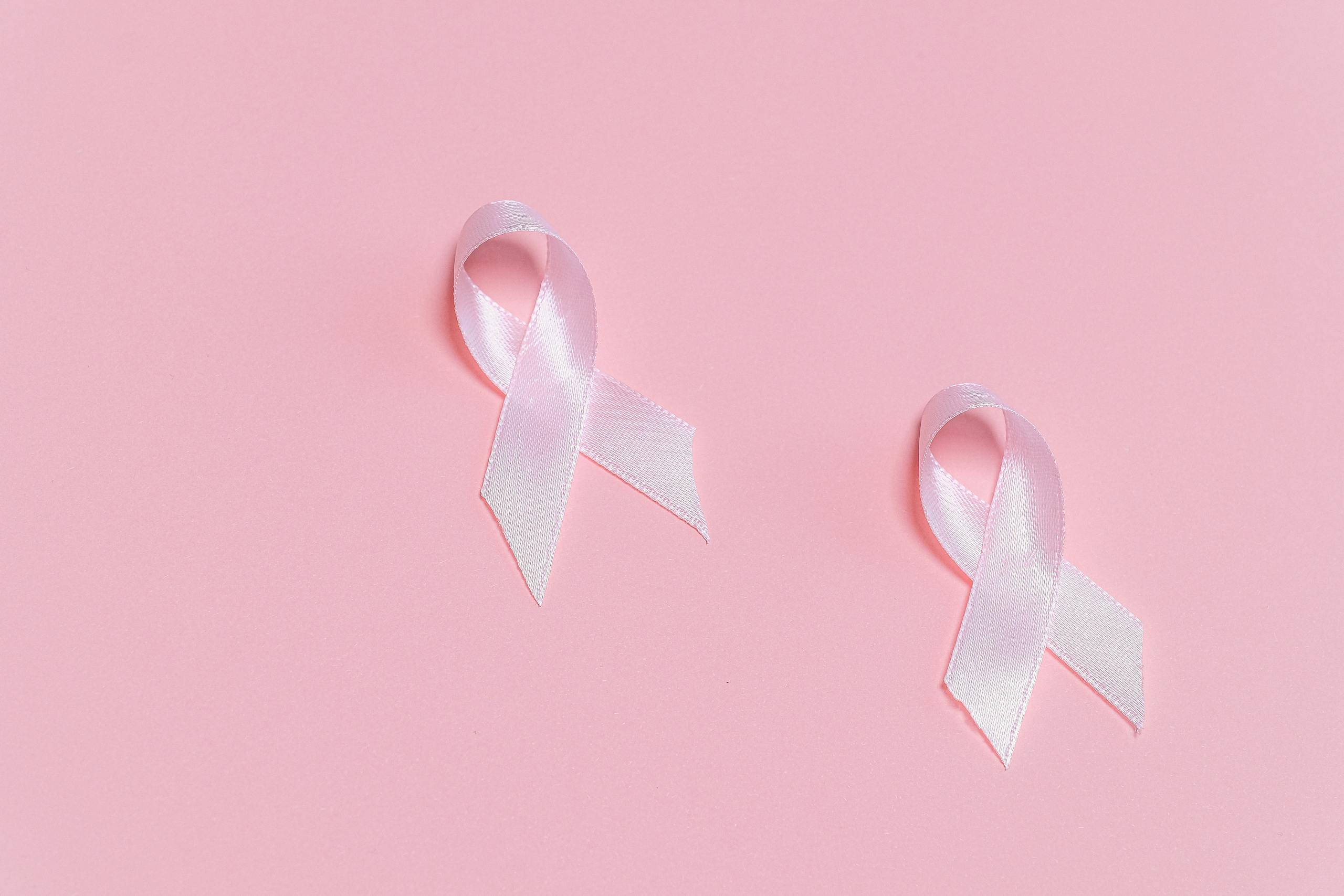 Pink ribbons symbolizing breast cancer awareness on a pink background.