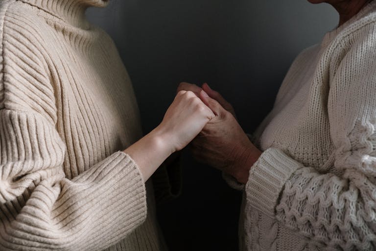 A close-up of two people holding hands, emphasizing warmth and connection.