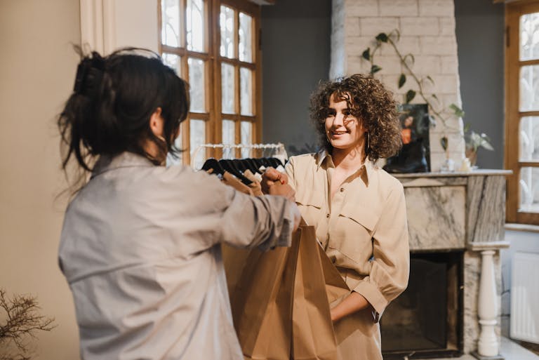 A customer receiving paper bags from a salesperson in a cozy boutique setting.