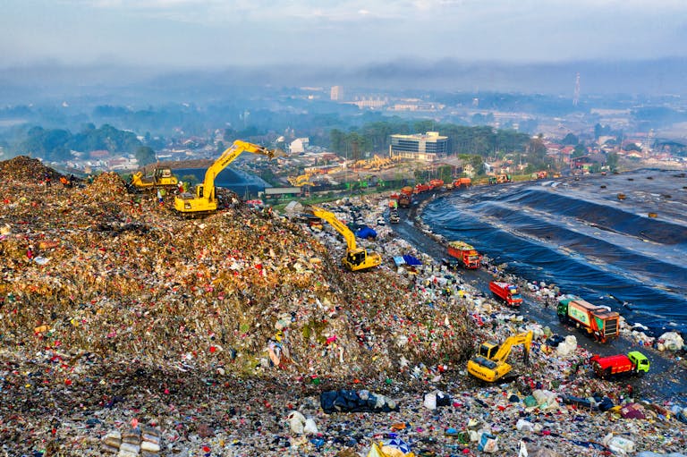 Aerial view showing heavy machinery at a landfill site in West Java, Indonesia.