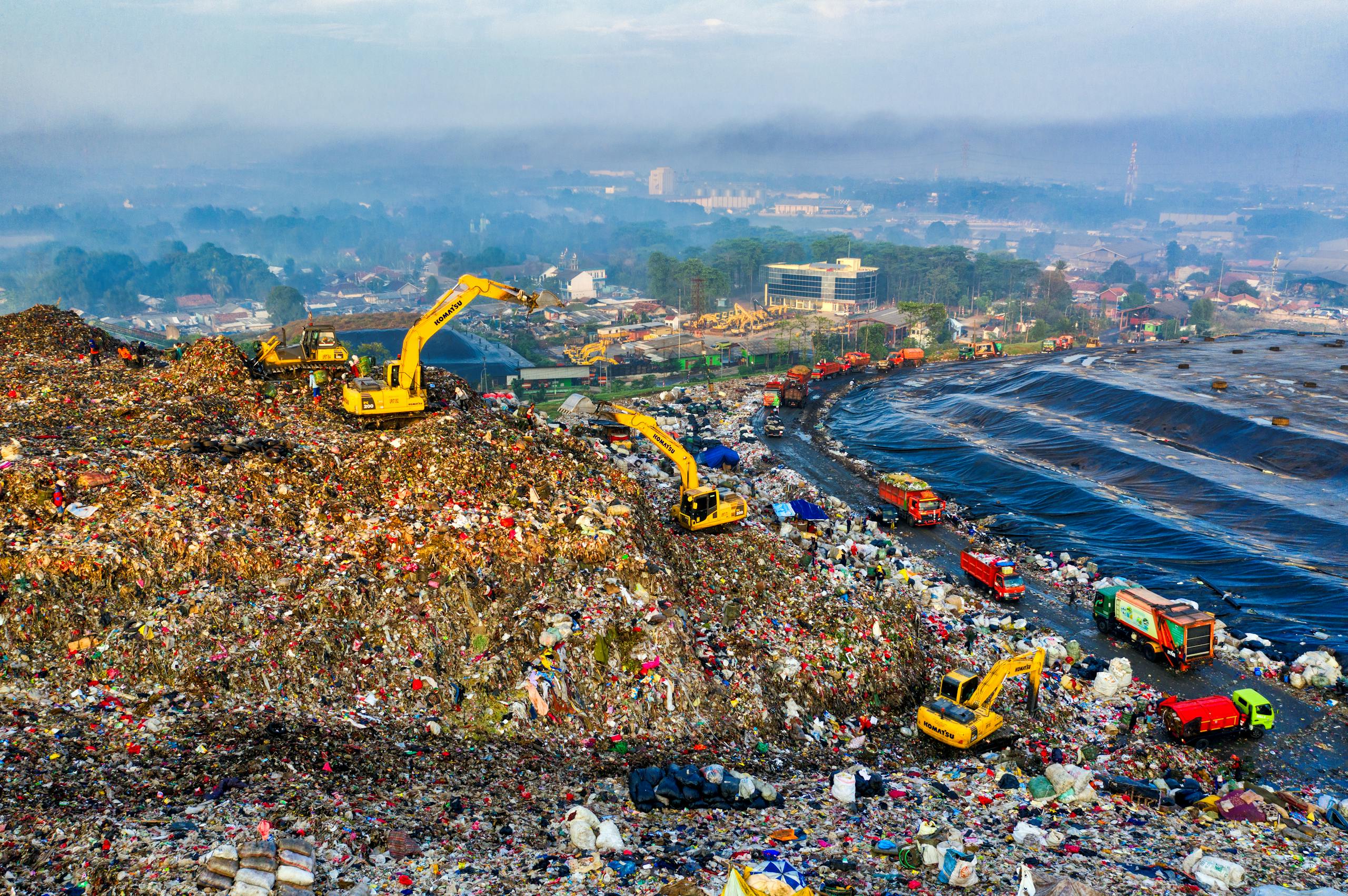 Aerial view showing heavy machinery at a landfill site in West Java, Indonesia.