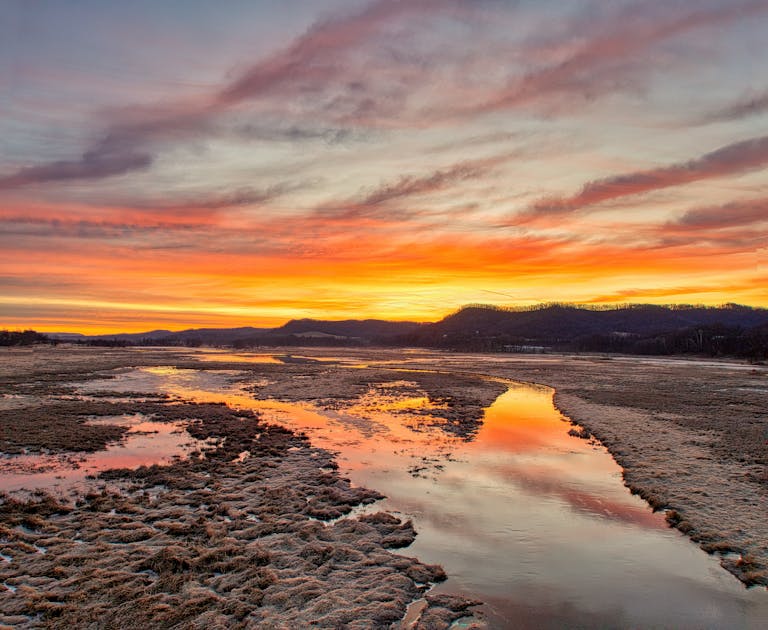 Captivating sunset over marshland near Alma, Wisconsin with vivid colors reflecting on water.