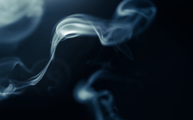 Ethereal white smoke swirling against a deep black backdrop, creating a mystical and abstract visual effect.
