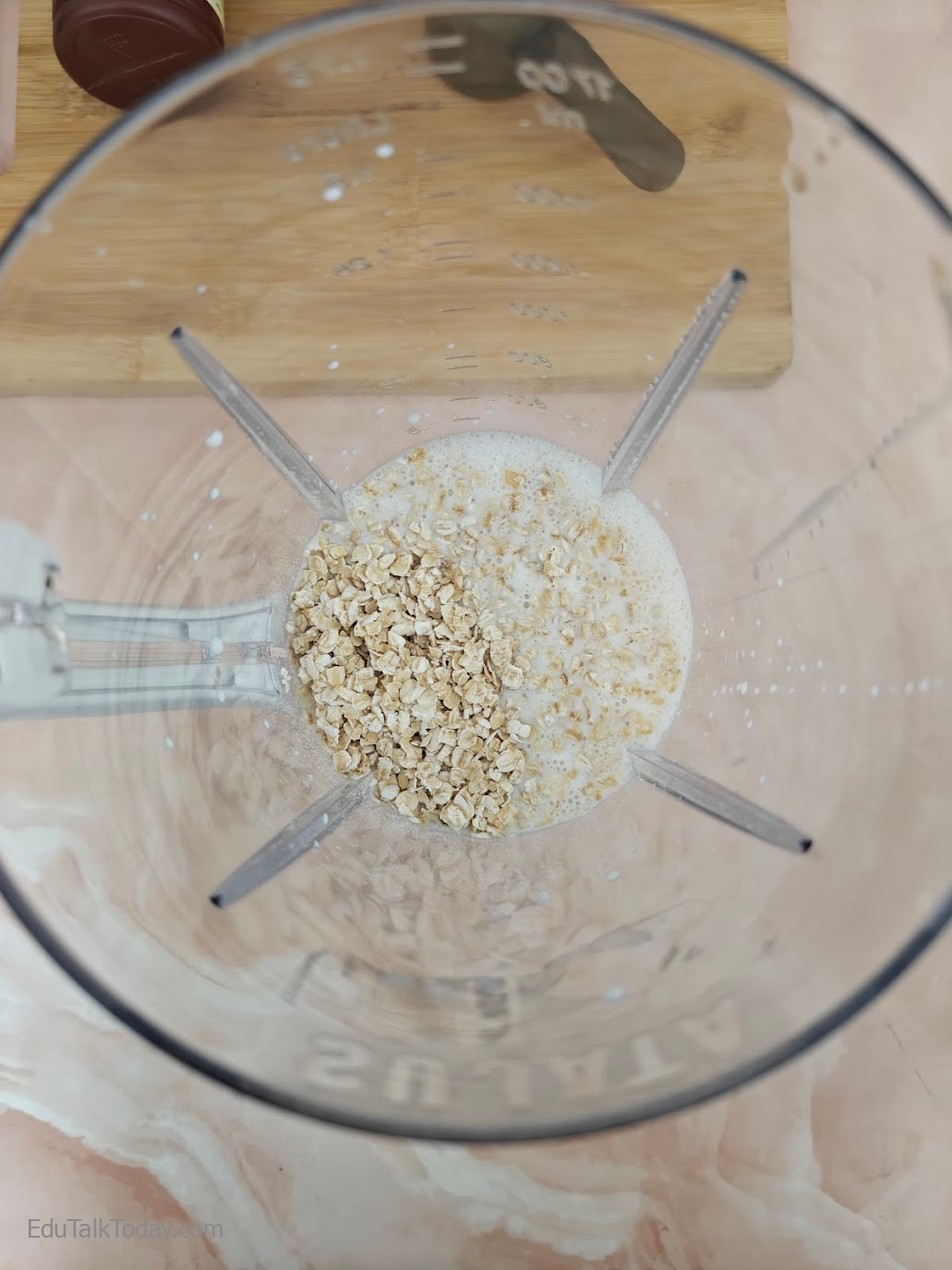 Rolled oats being added to blender with milk for peanut butter oats smoothie